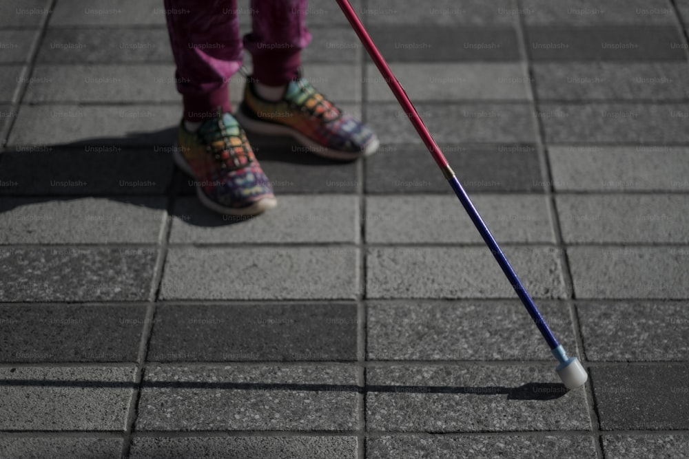 a person standing on a sidewalk with a cane