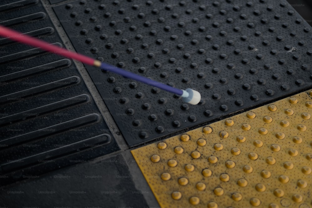 a yellow and black street sign with a blue handle