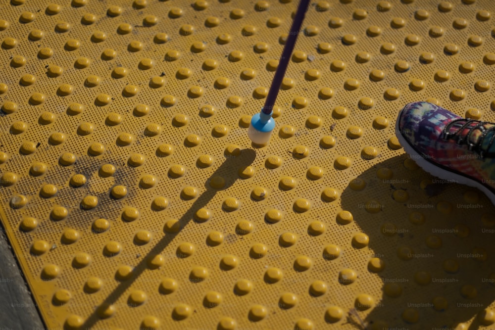uma pessoa em pé em uma plataforma amarela com uma escova de dentes azul