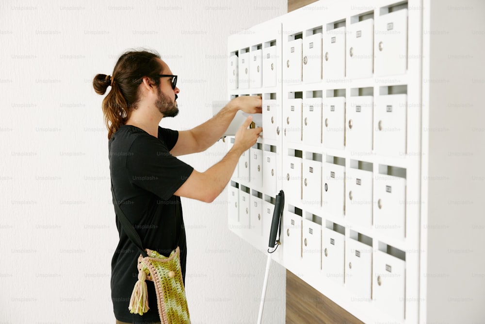 um homem colocando um monte de correio em uma parede