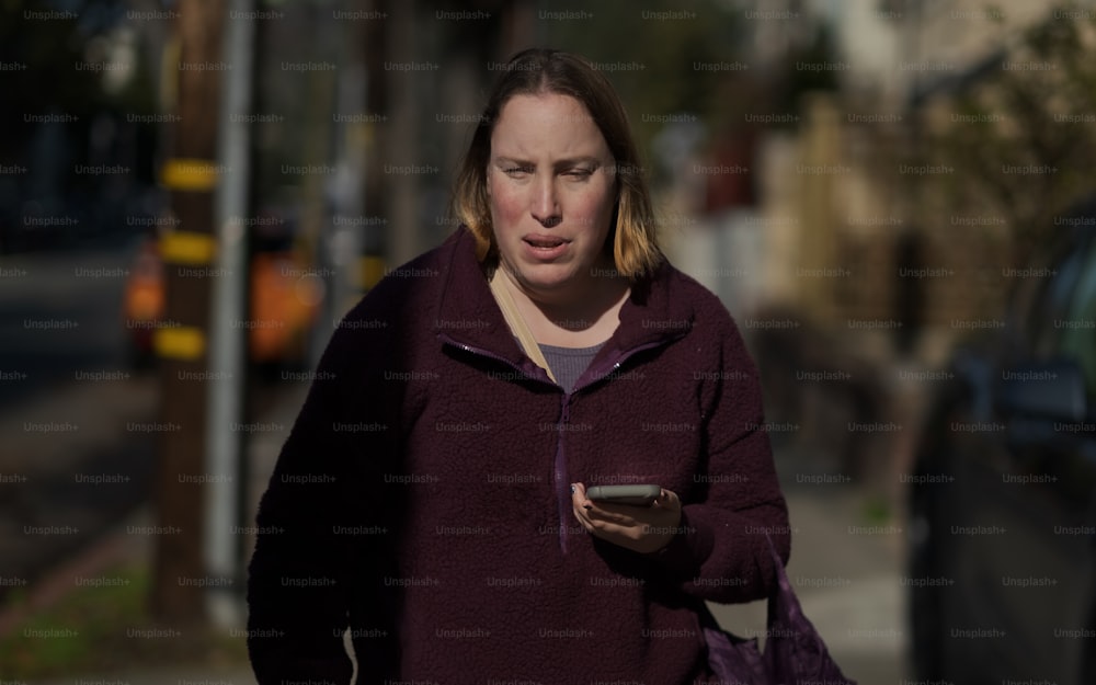 Une femme marchant dans la rue tout en regardant son téléphone portable