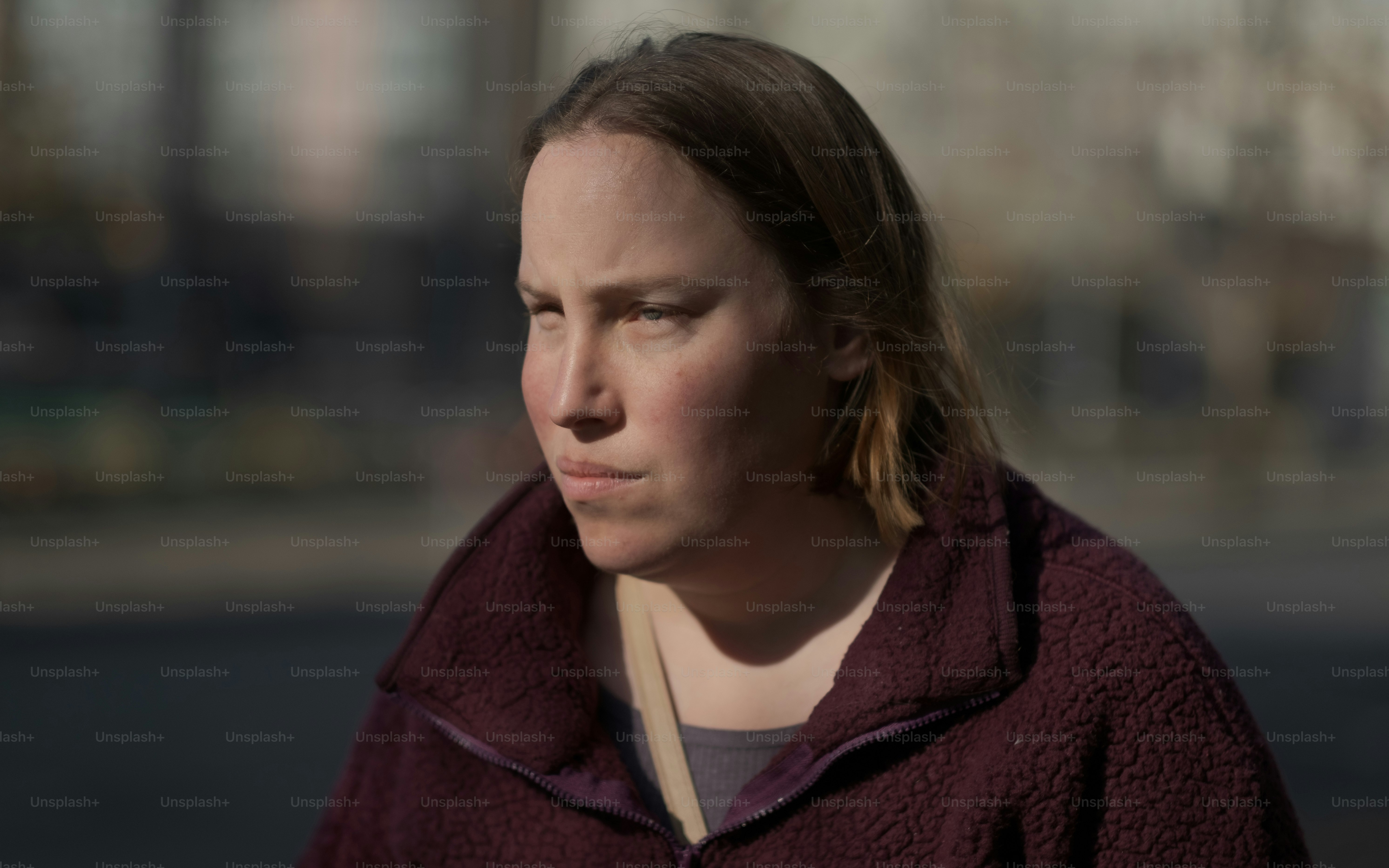 a woman in a maroon jacket looking off into the distance