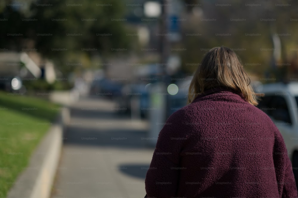 uma mulher andando pela rua em um suéter roxo