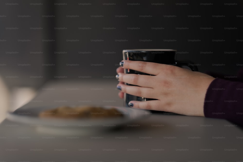 a person holding a coffee mug over a plate of food