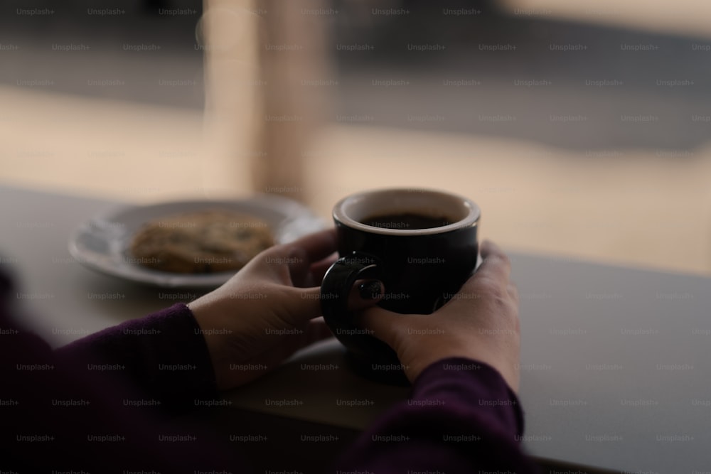 a person holding a cup of coffee and a plate of cookies