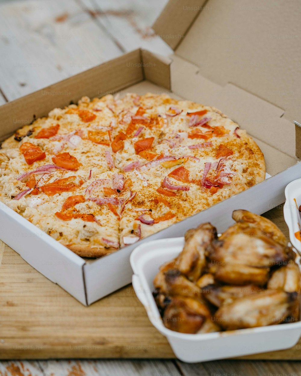 una caja de alitas de pollo y una caja de pizza