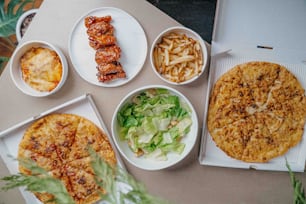 a table topped with plates of food and pizza