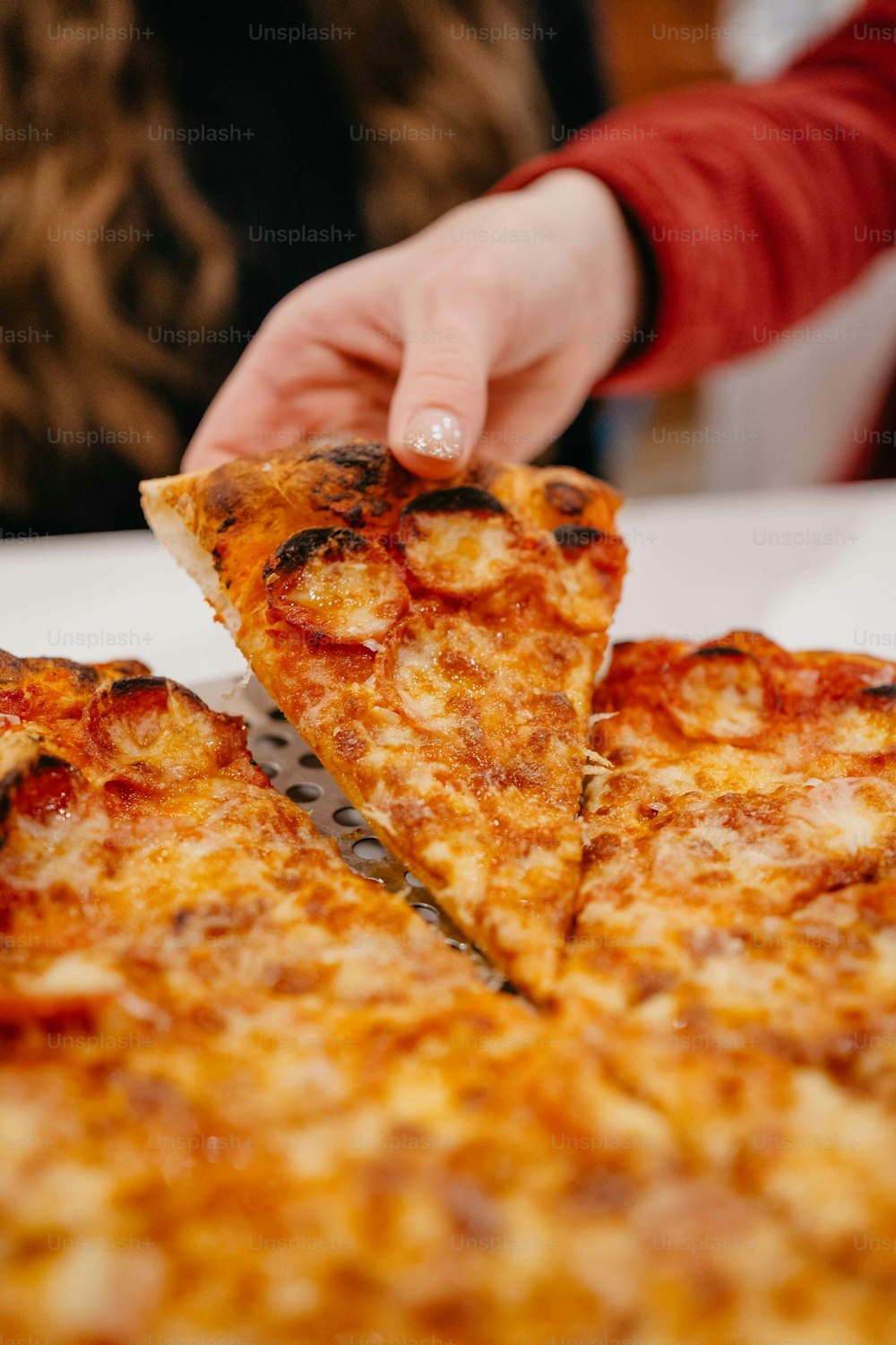 a person cutting a slice of pizza with a knife