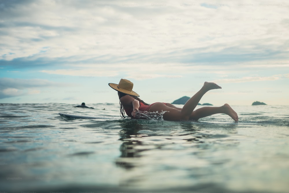 uma mulher deitada em uma prancha de surf no oceano