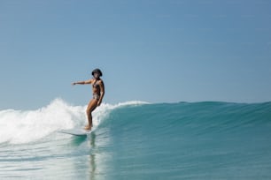 uma mulher que monta uma onda em cima de uma prancha de surf
