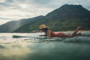 a woman laying on a surfboard in the ocean