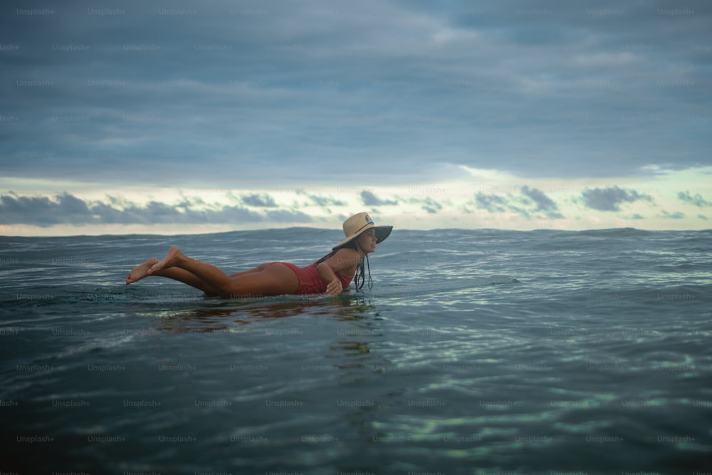 a woman laying on a surfboard in the ocean
