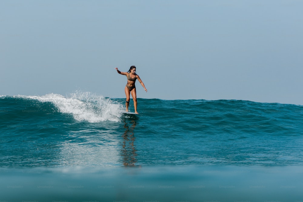 a woman riding a wave on top of a surfboard