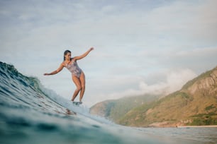 a woman riding a wave on top of a surfboard