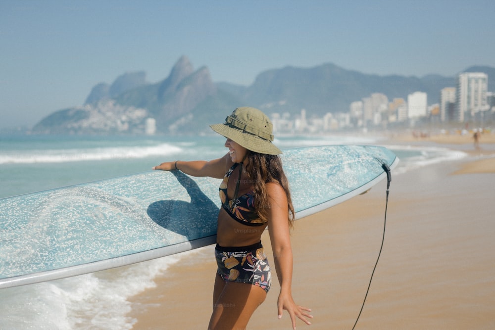 Una mujer en bikini sosteniendo una tabla de surf en la playa