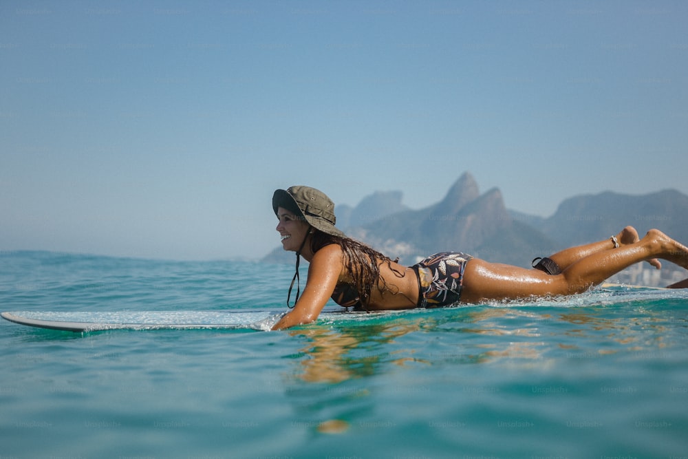 a woman laying on a surfboard in the ocean