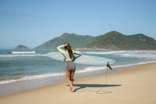 Eine Frau steht am Strand und hält ein Surfbrett in der Hand