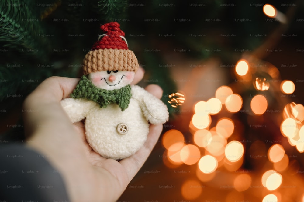 a person holding a small snowman ornament in their hand