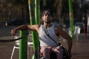 a man in a wheelchair leaning against a pole