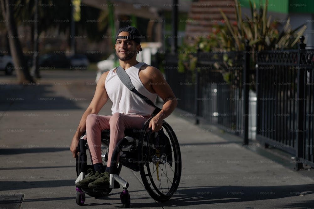 um homem sentado em uma cadeira de rodas em uma calçada