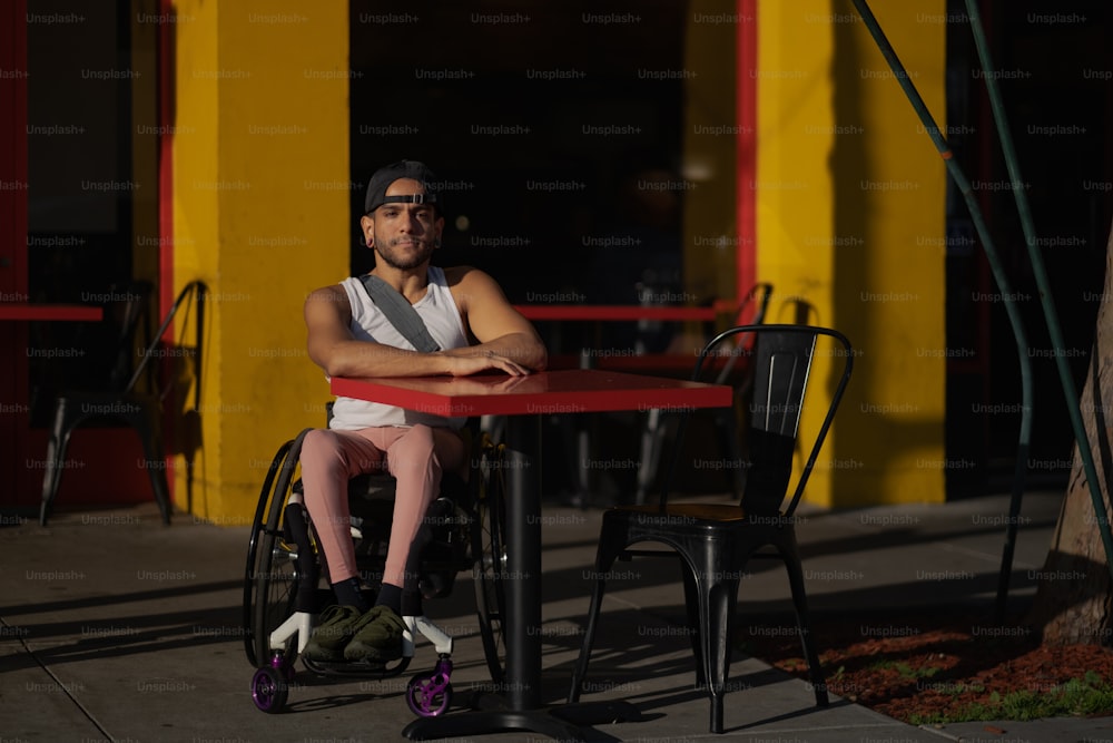 a man sitting at a table in front of a yellow building