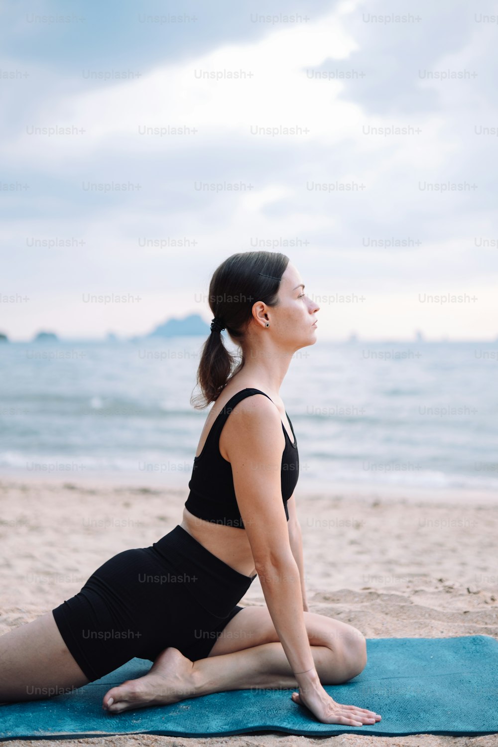 Une femme est assise sur une serviette sur la plage