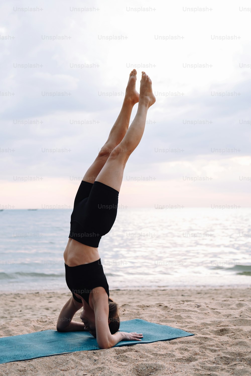 uma mulher que faz um handstand em uma praia
