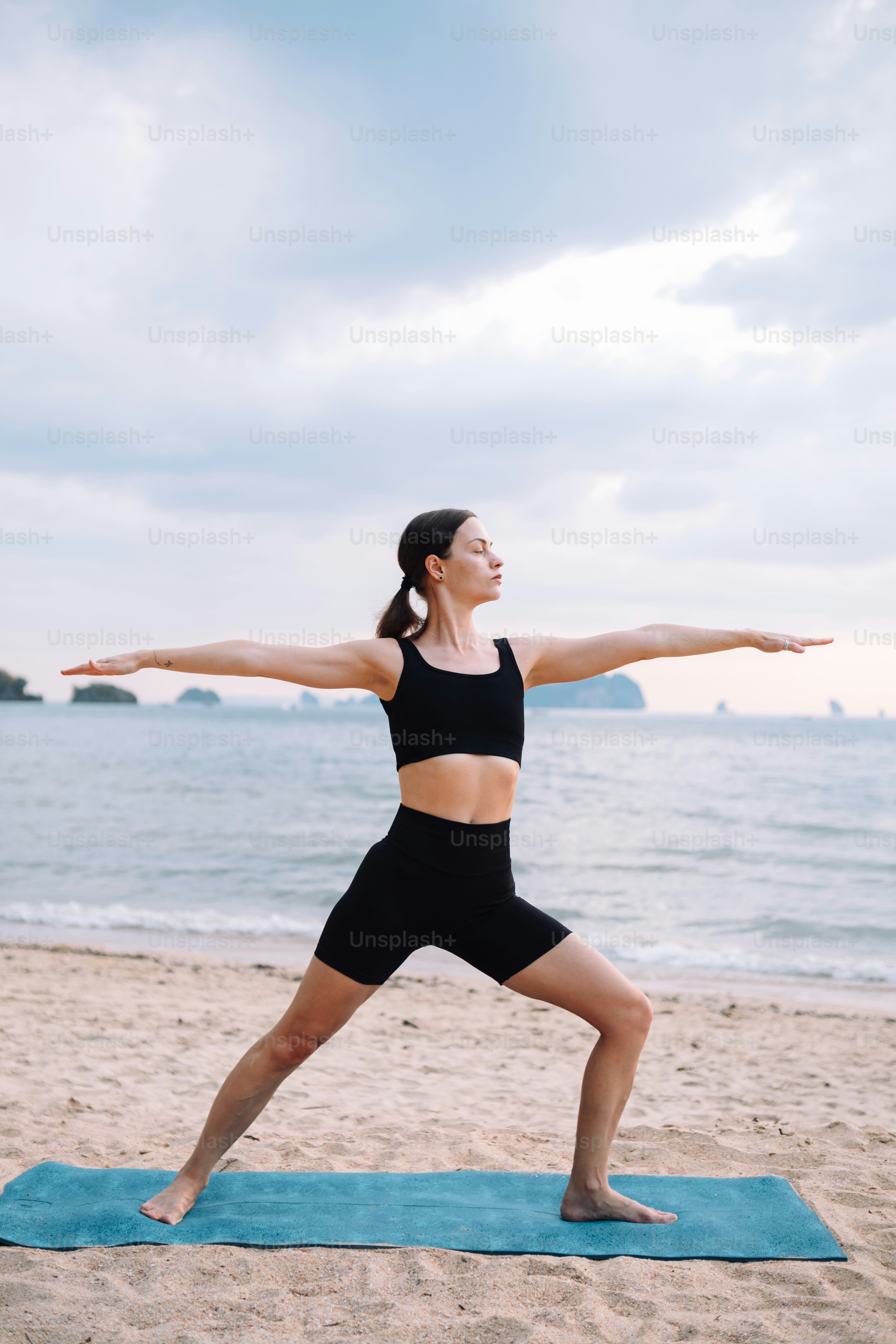 a woman is doing yoga on the beach