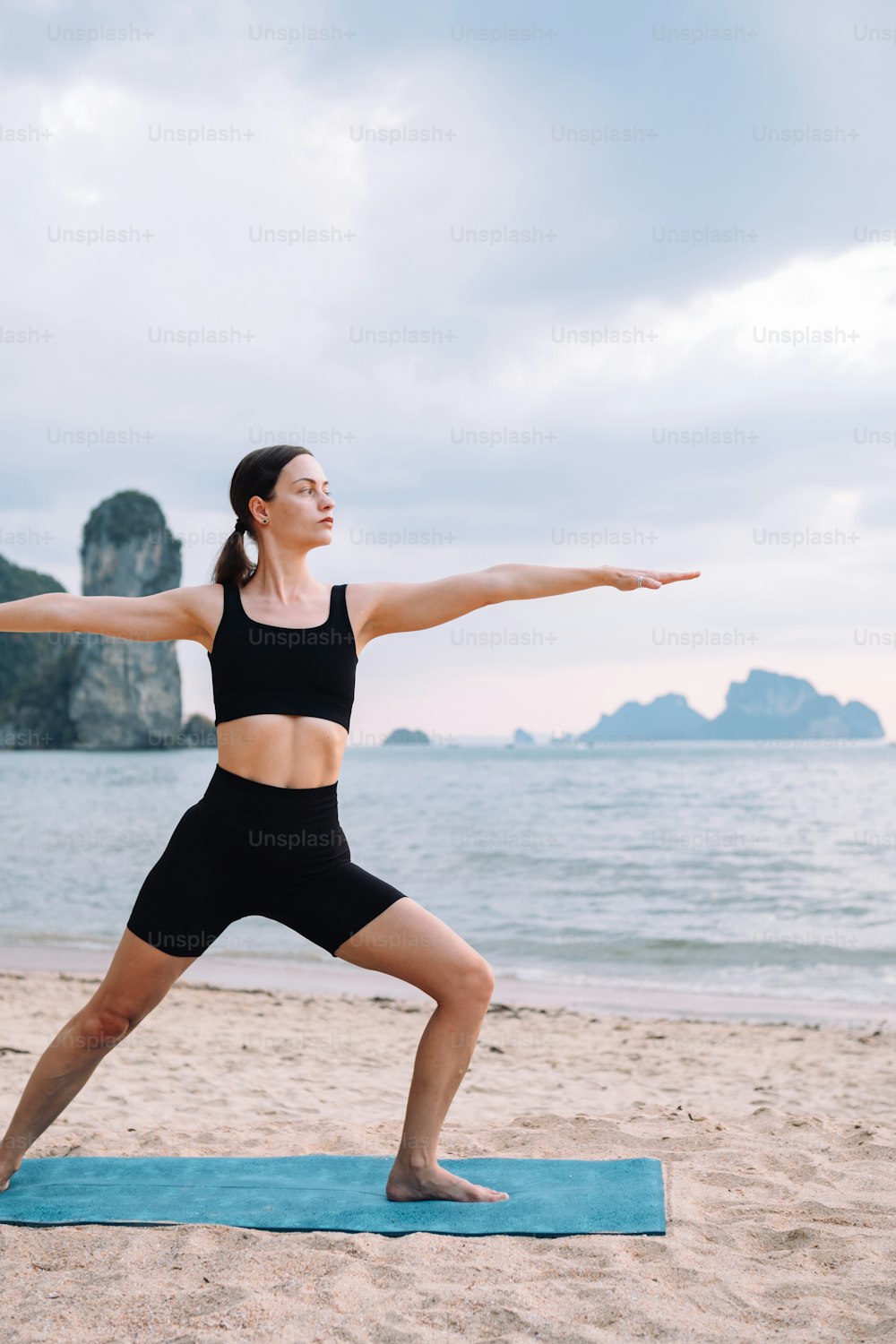Une femme fait du yoga sur la plage