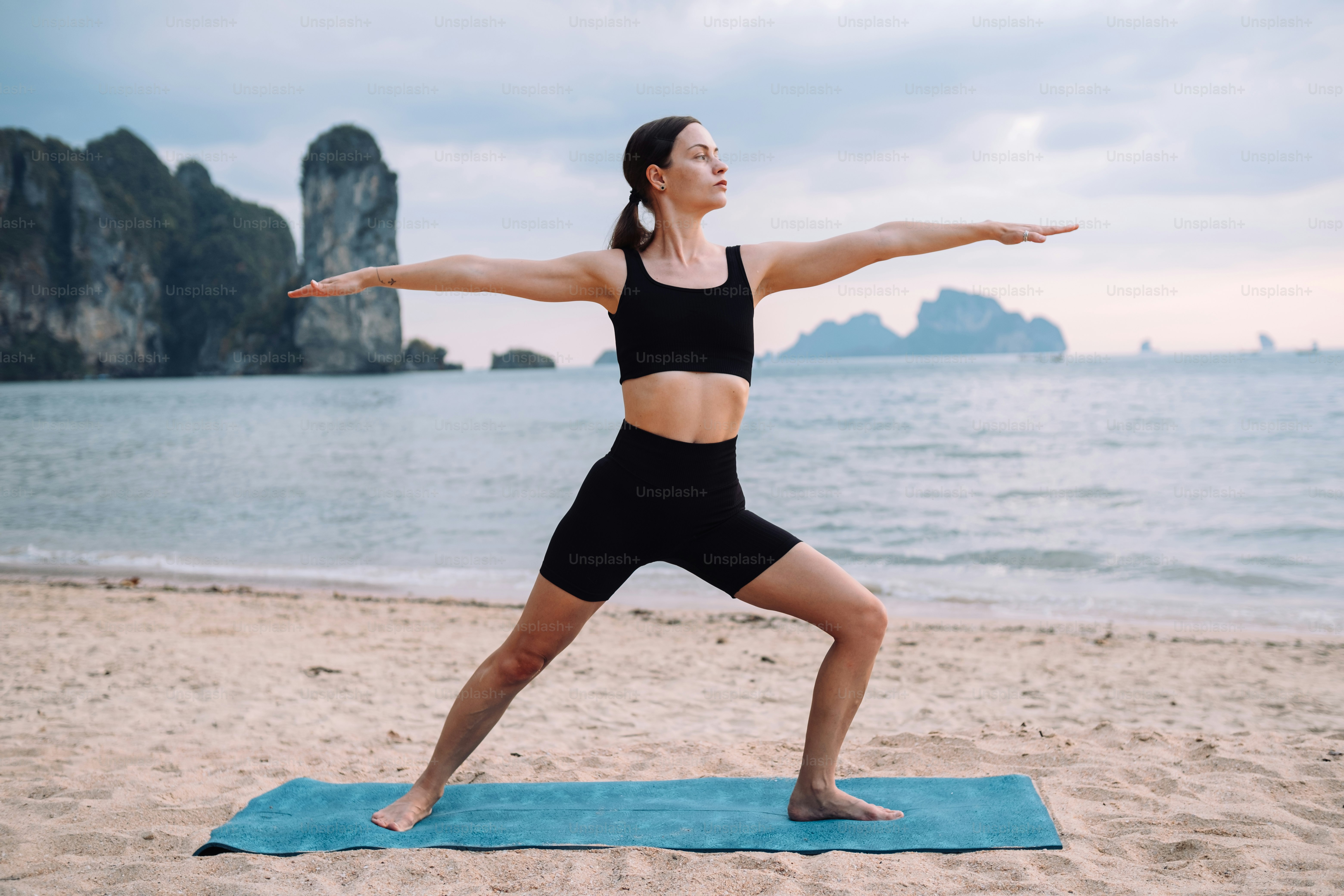 Una mujer está haciendo yoga en la playa