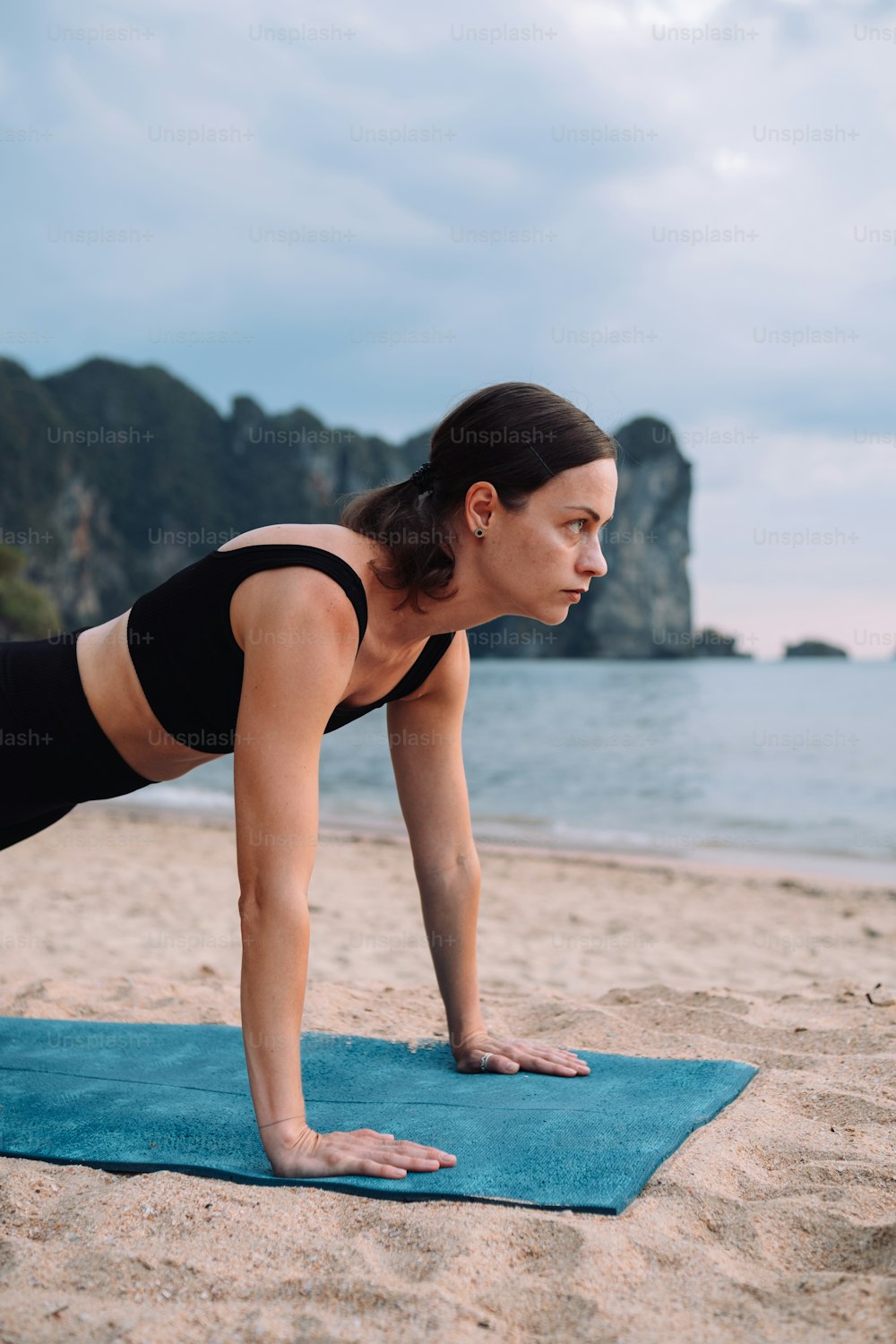 a woman is doing a push up on the beach