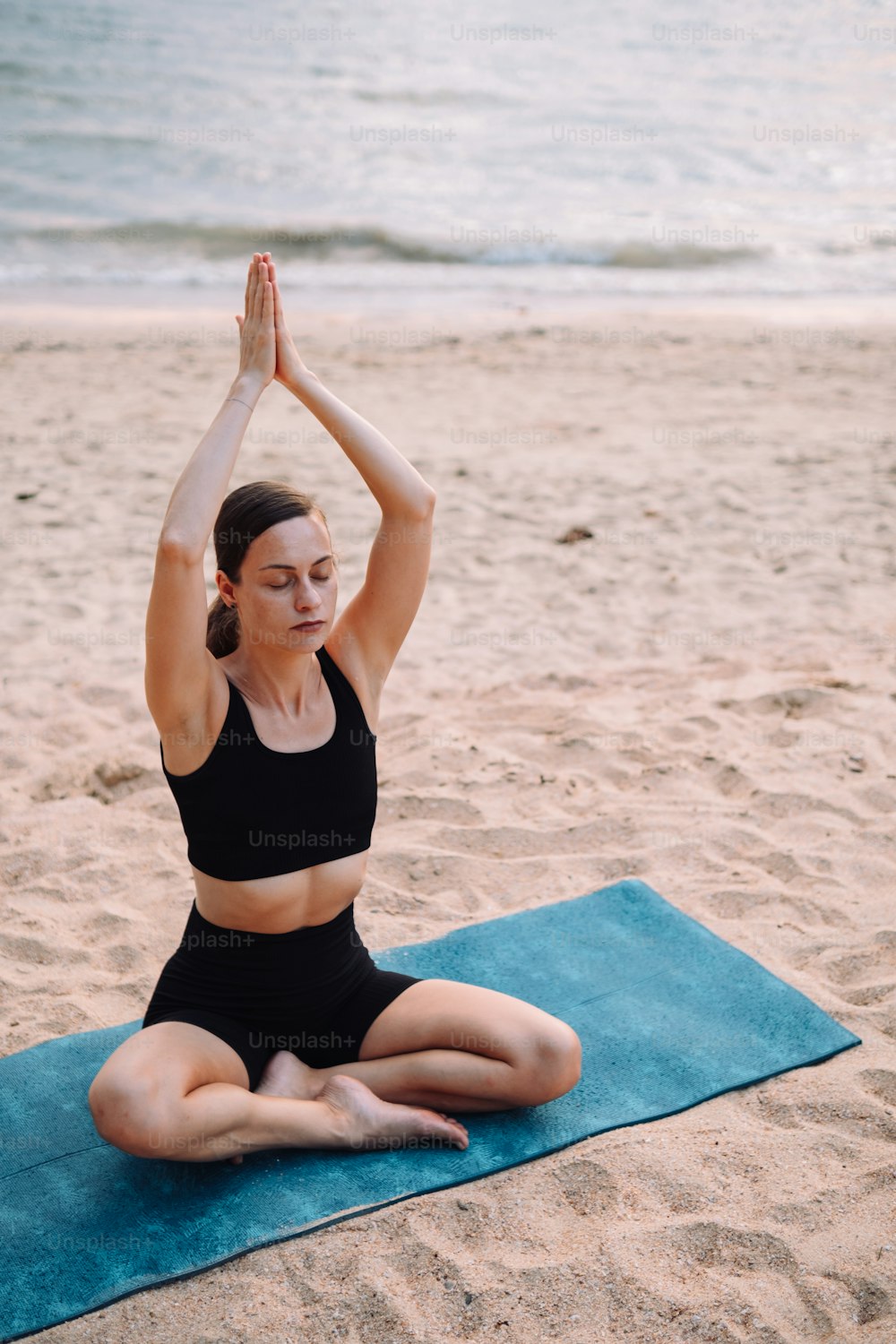 uma mulher está fazendo yoga na praia