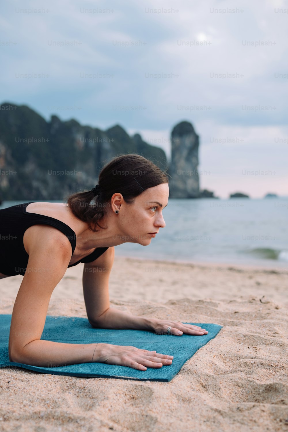a woman is doing push ups on a towel on the beach