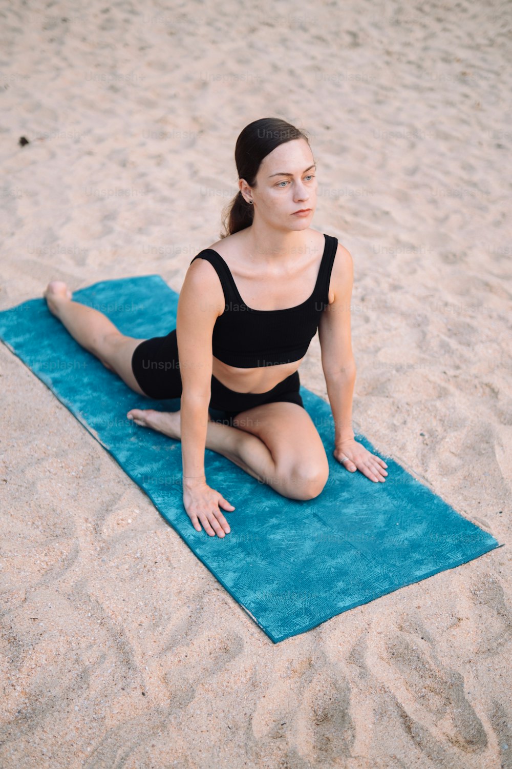 Una mujer está sentada en una toalla en la playa