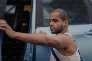 a man in a tank top getting out of a car