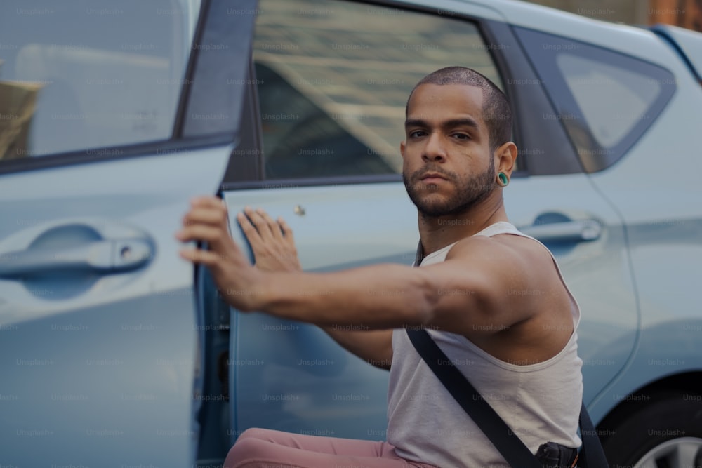 Un hombre sosteniendo un cigarrillo frente a un automóvil