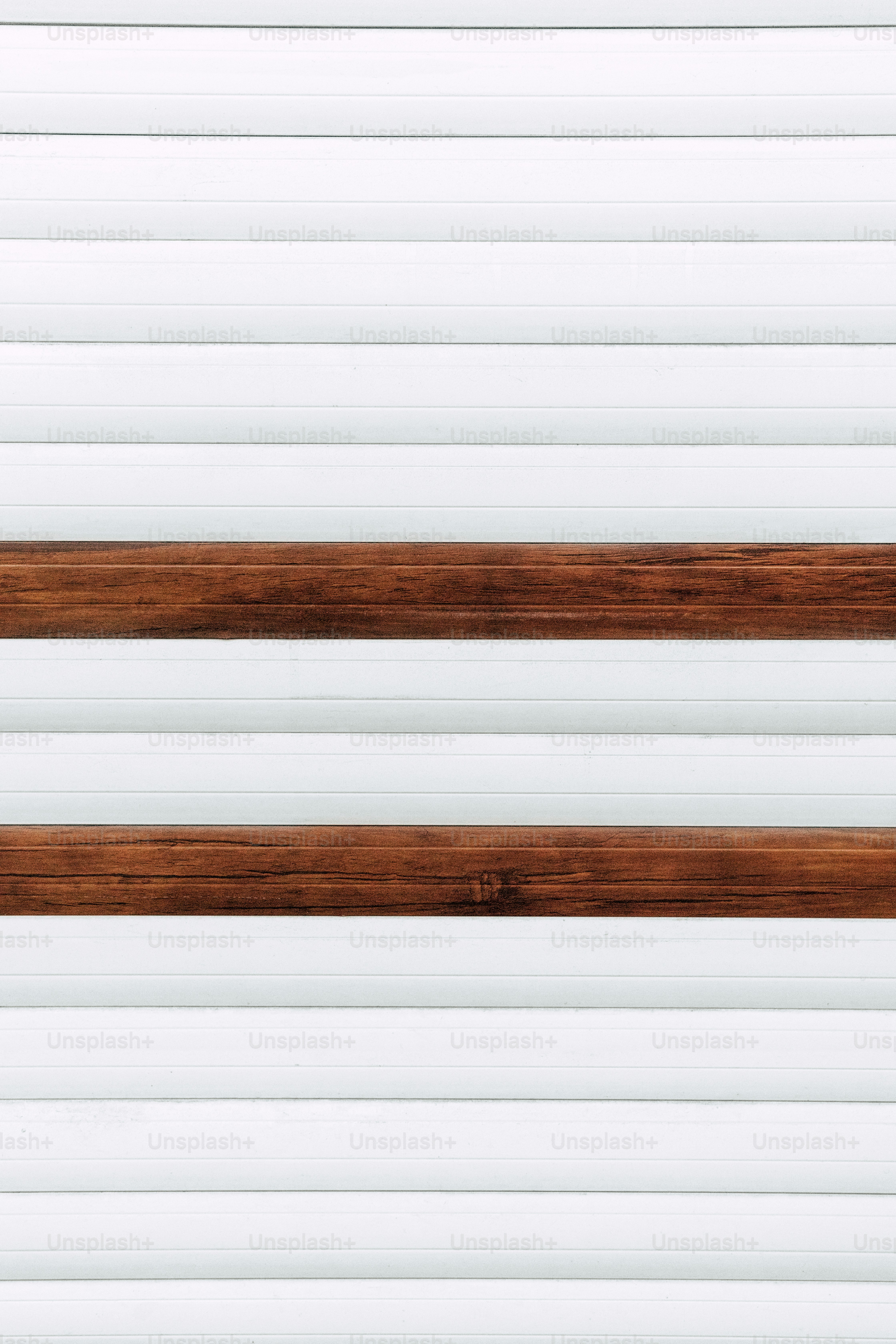 a close up of a wooden bench against a white wall
