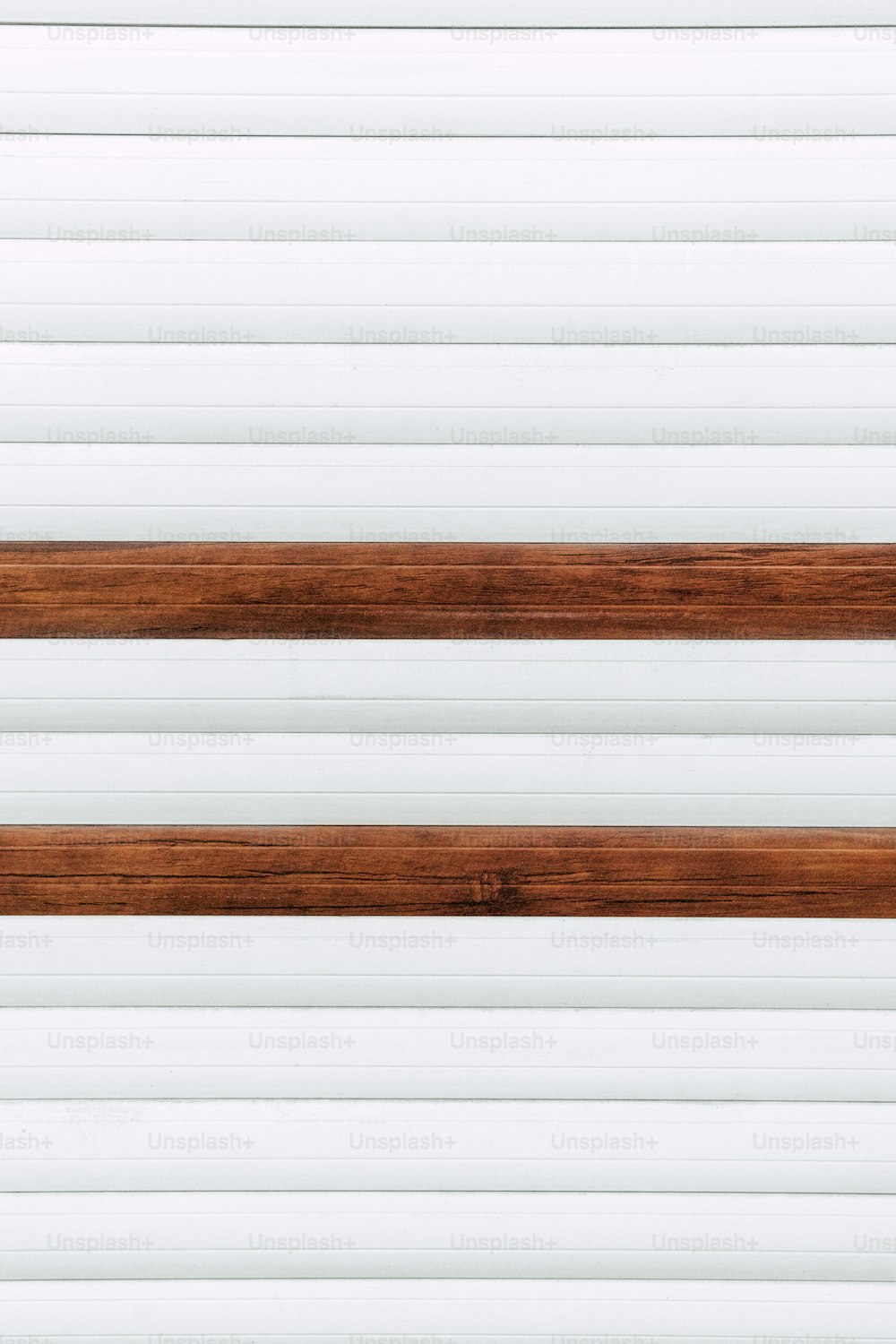 a close up of a wooden bench against a white wall