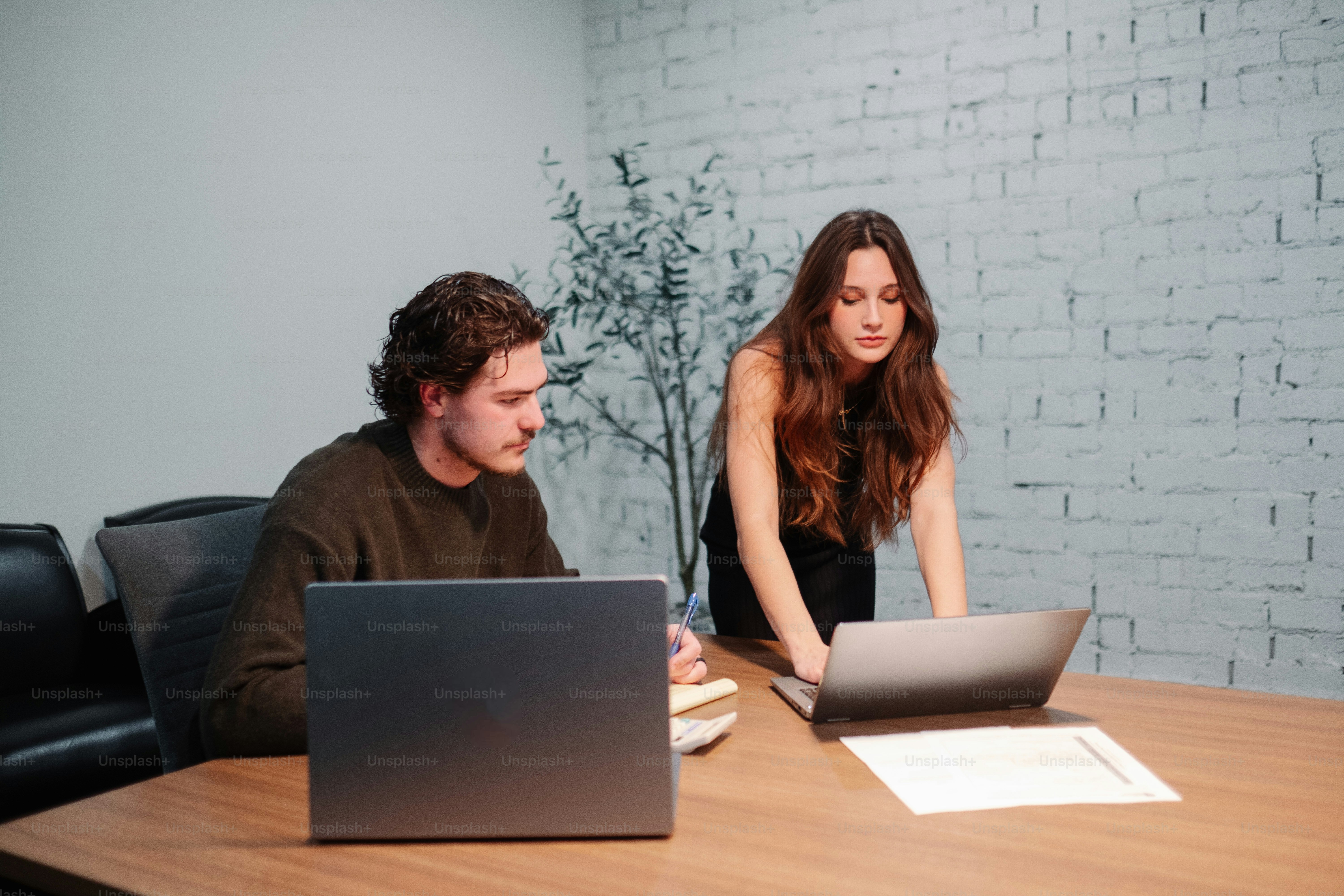 a man and a woman sitting at a table with laptops