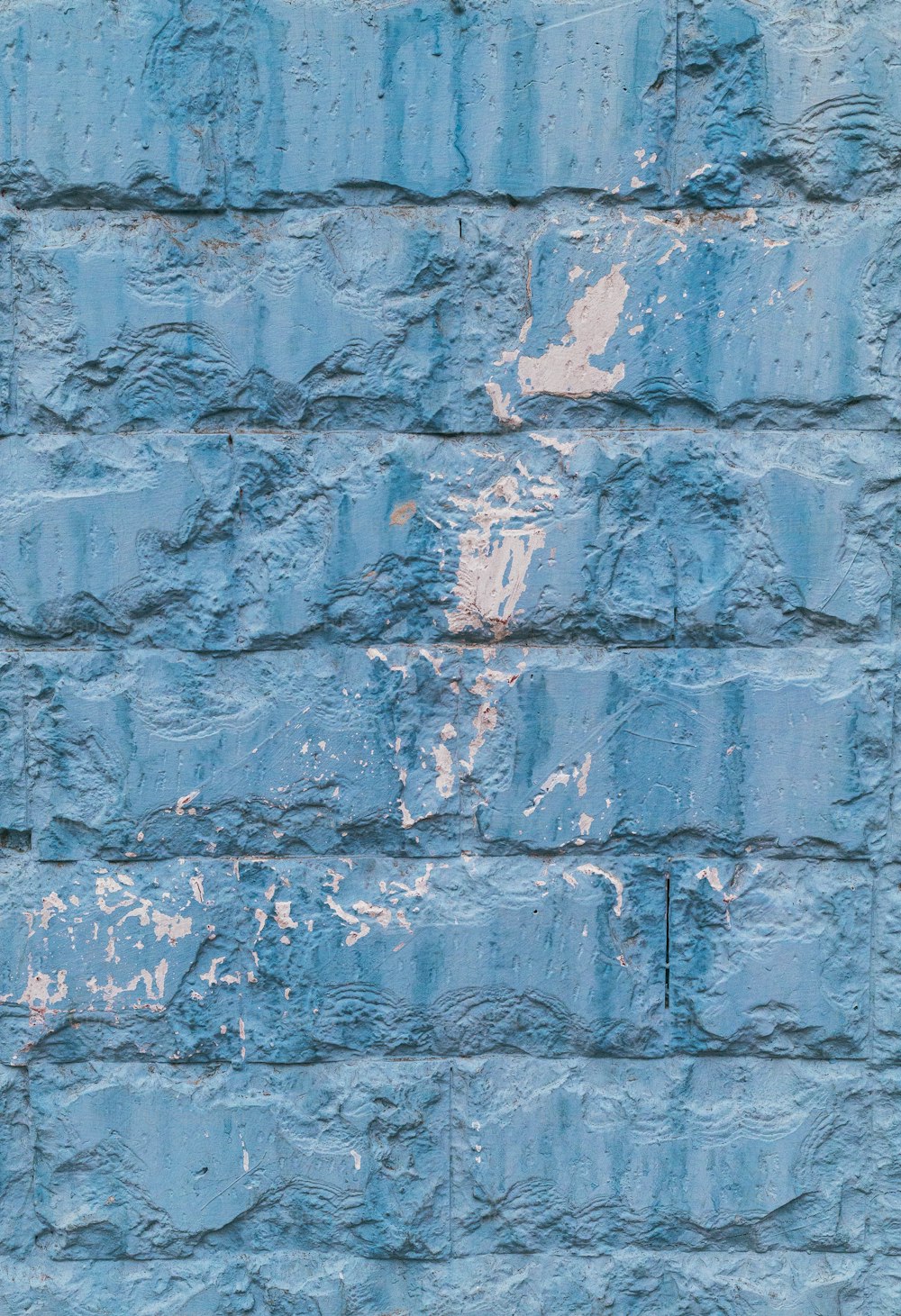 a blue brick wall with peeling paint on it