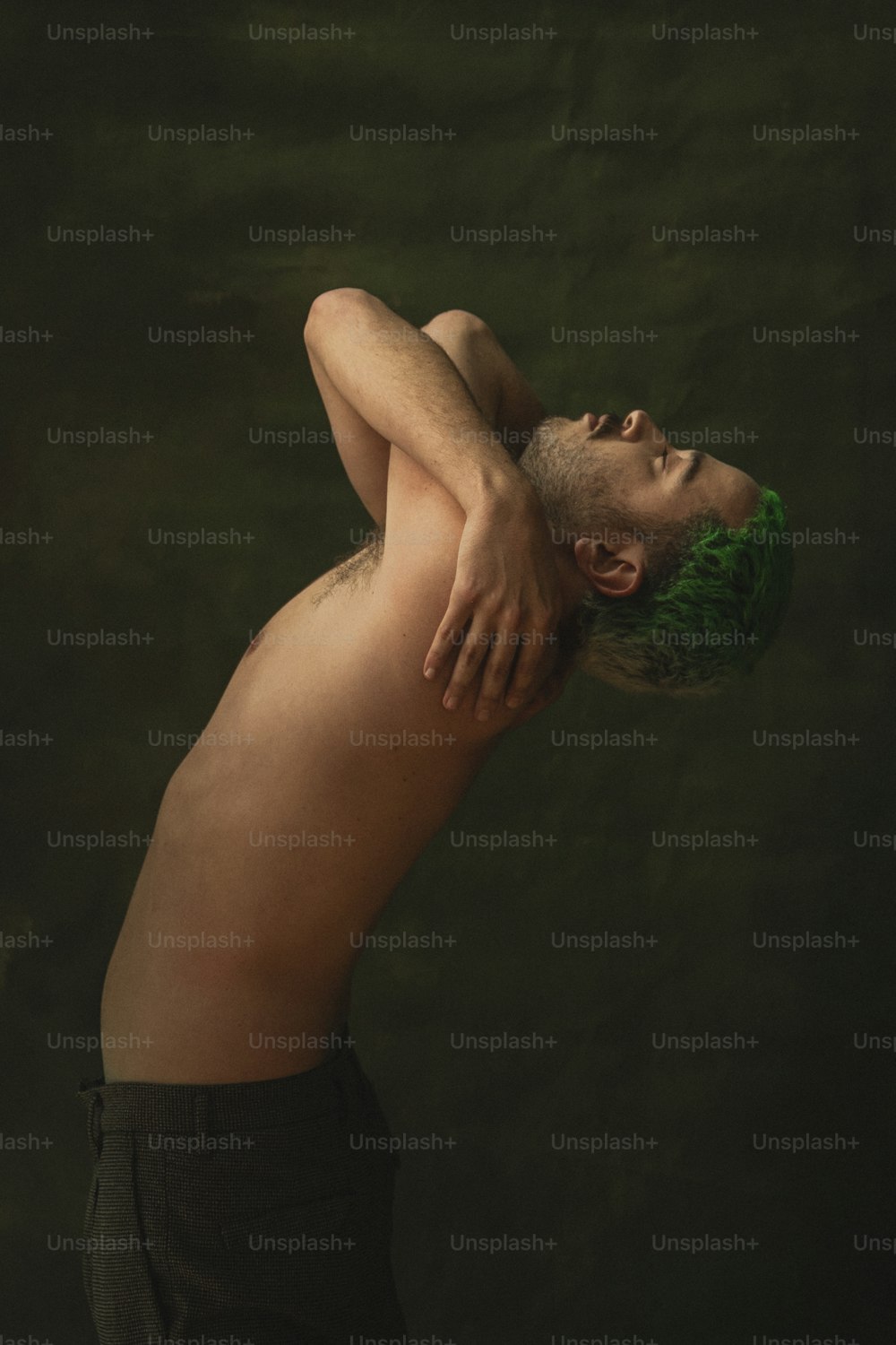 Un hombre sin camisa con cabello verde y barba
