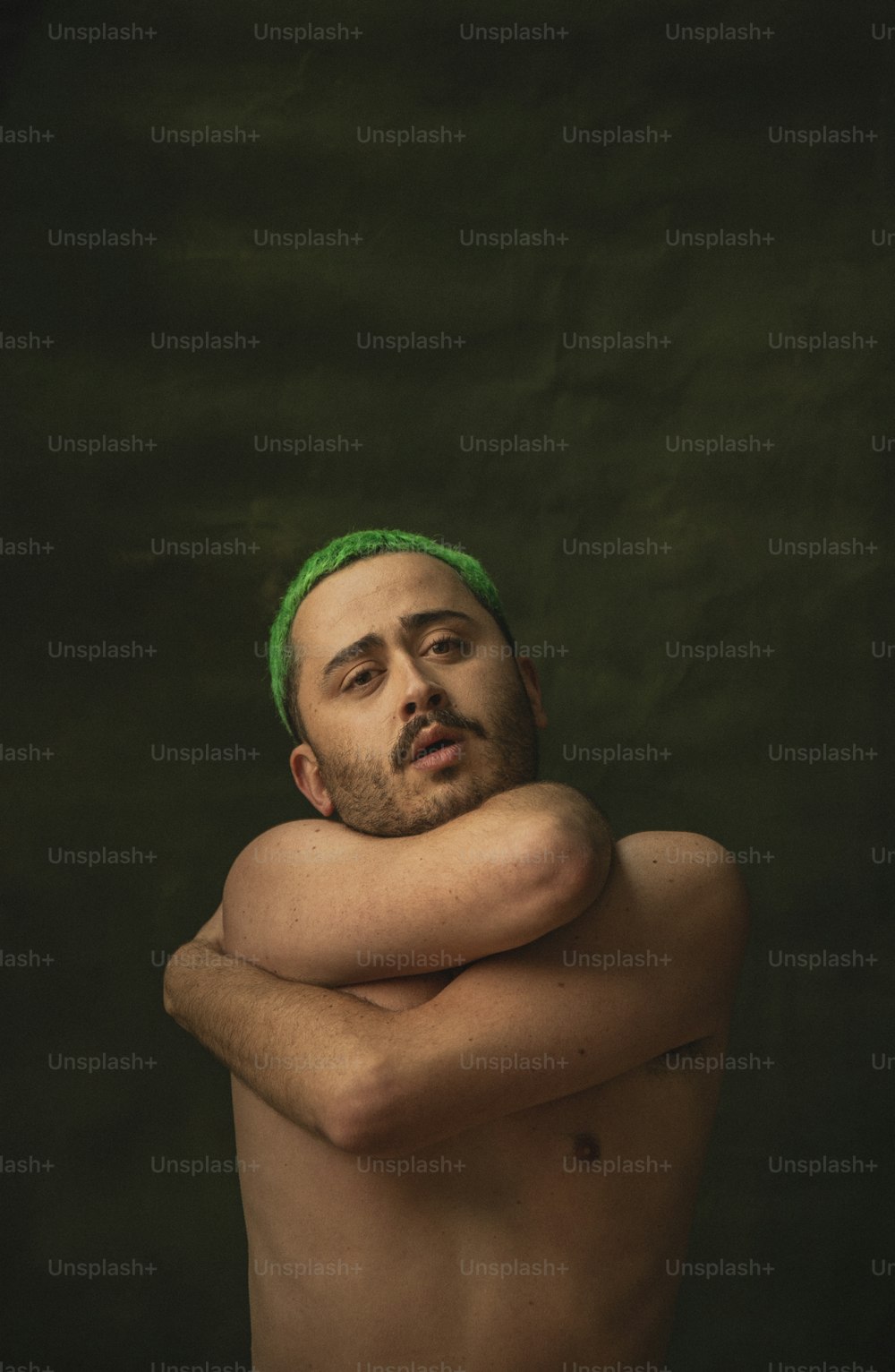 Un hombre sin camisa con una diadema verde puesta