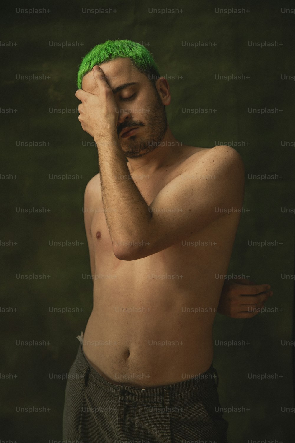 a shirtless man with green hair covering his eyes