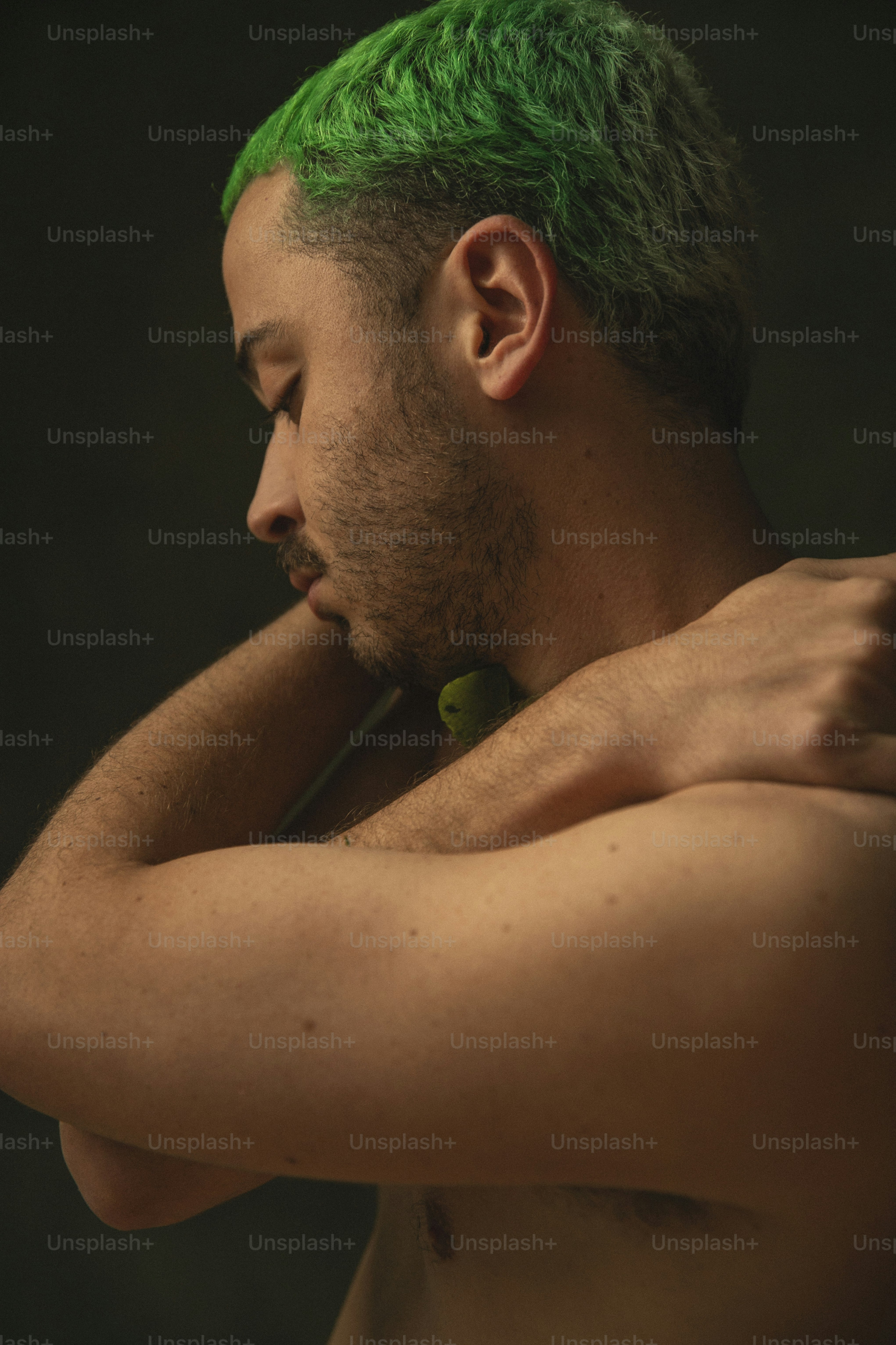 a shirtless man with green hair and piercings