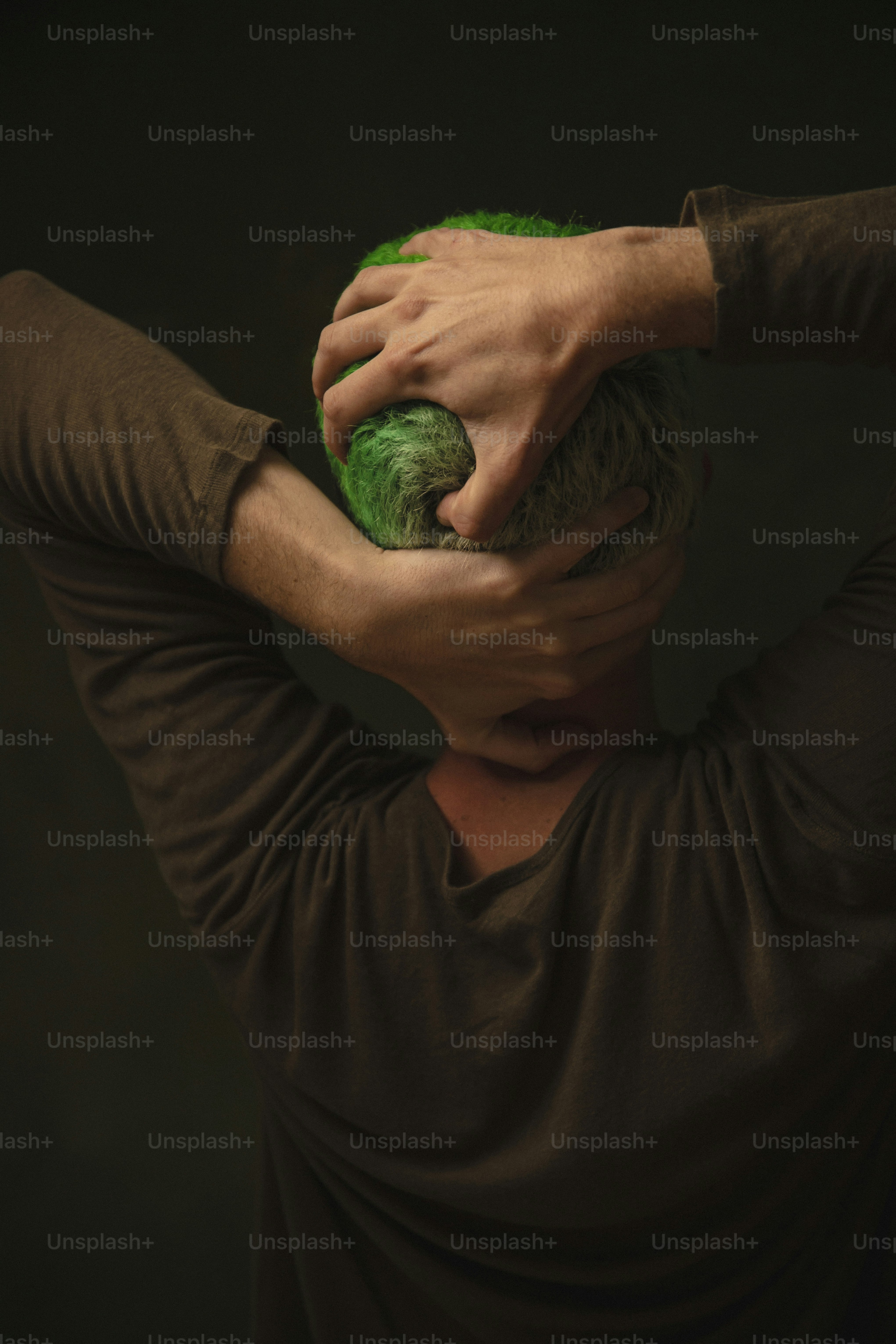 a man with green hair covering his face