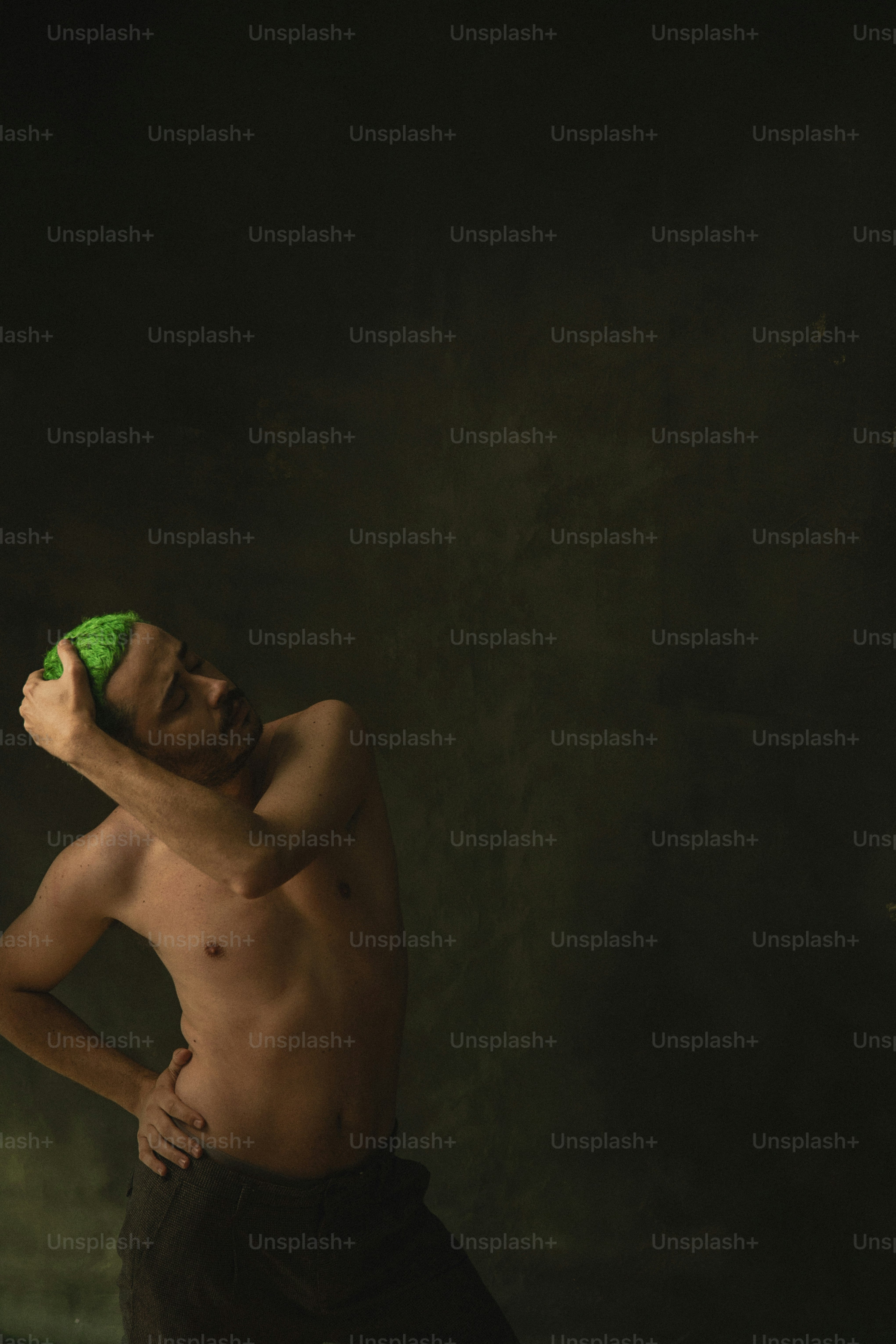 Un homme torse nu tenant un objet vert dans sa main