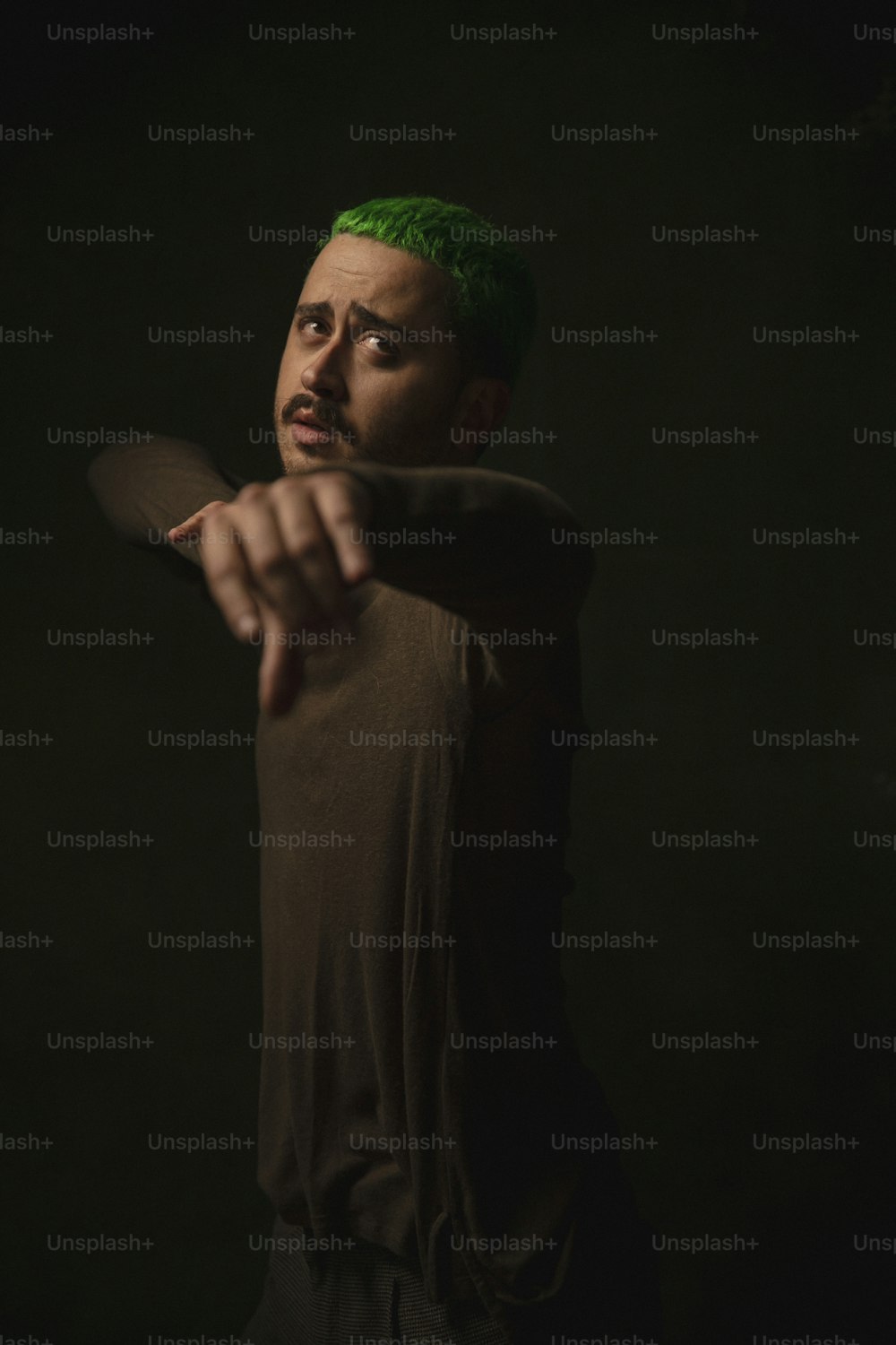 Ein Mann mit grünen Haaren, der eine Waffe richtet