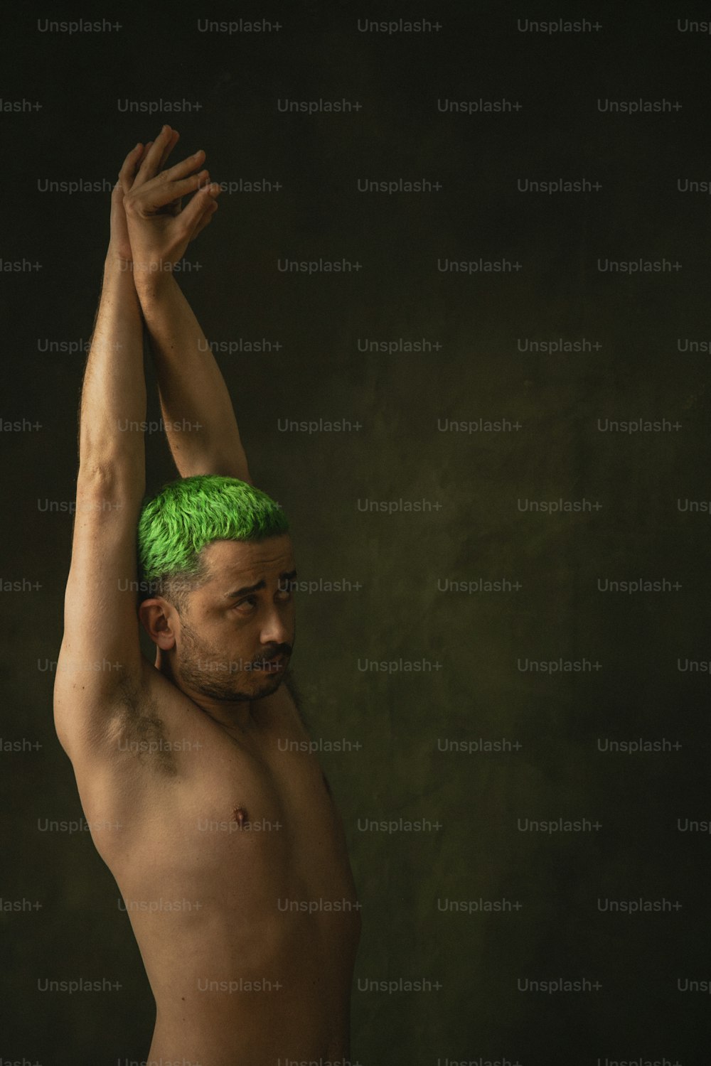 Un uomo a torso nudo con una parrucca verde in testa