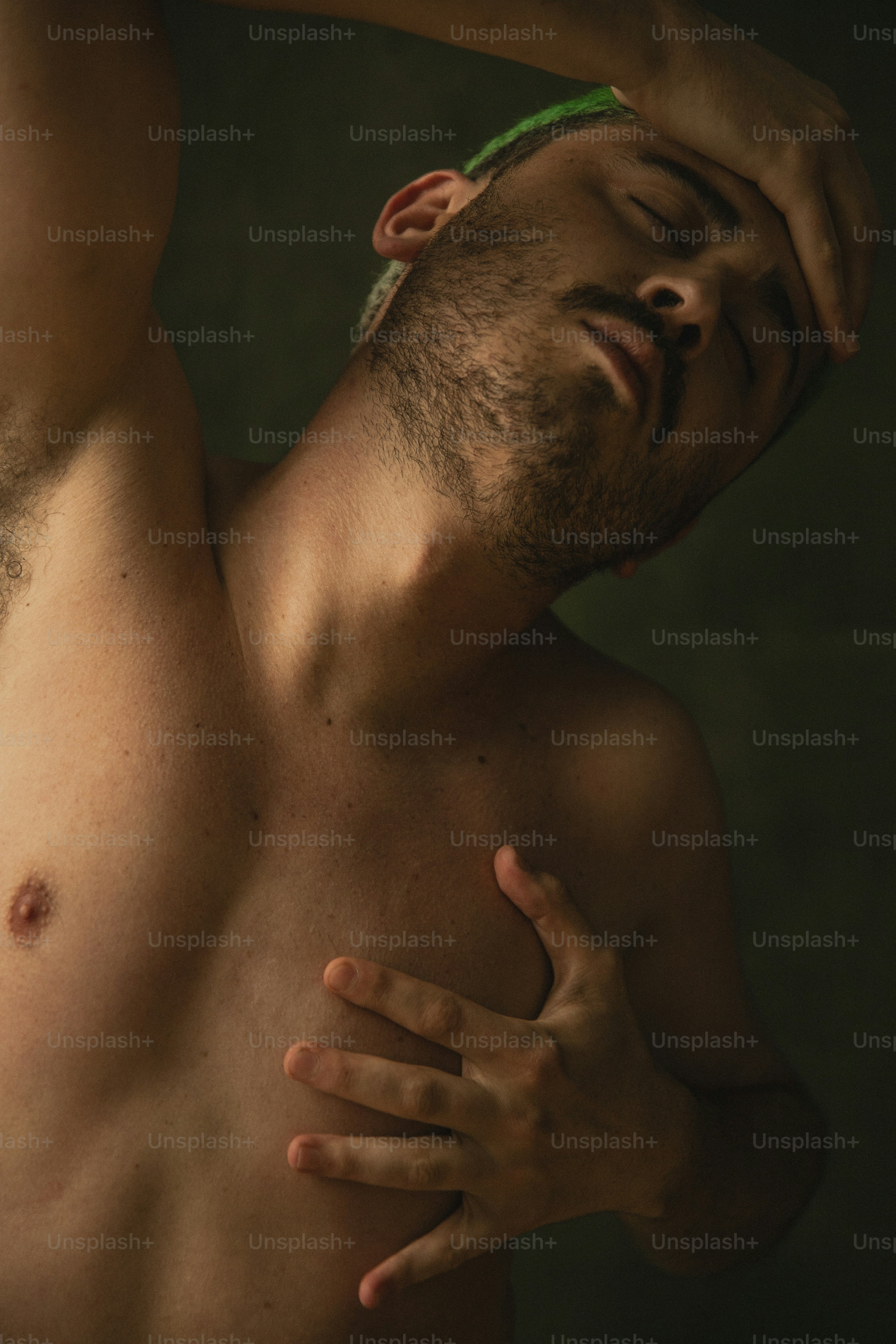 a shirtless man holding his head in his hands