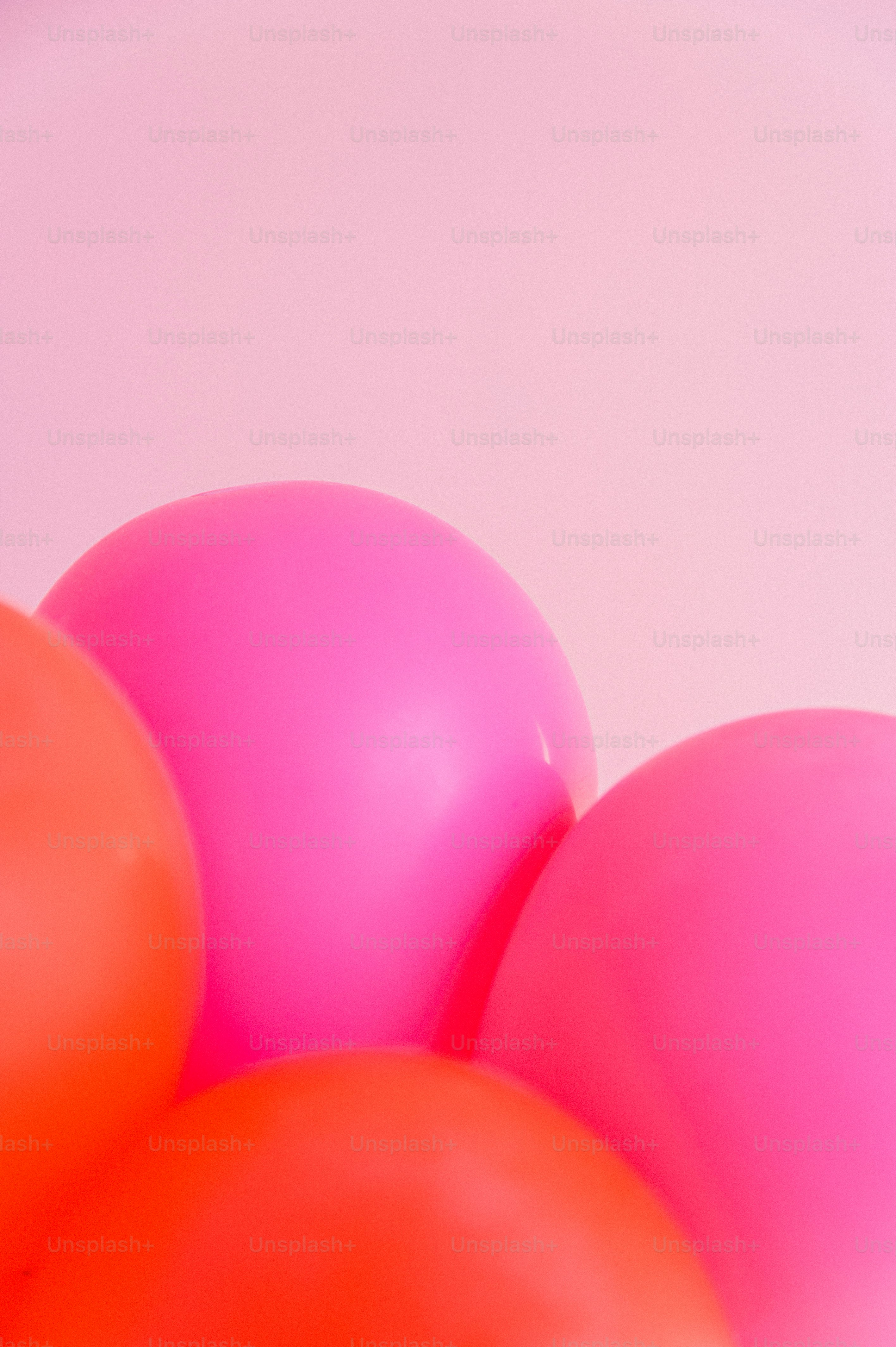 ein Haufen rosa und orangefarbener Luftballons vor weißem Hintergrund